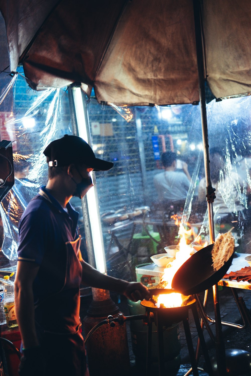 A street food vendor cooking over high flames at a busy night stall.